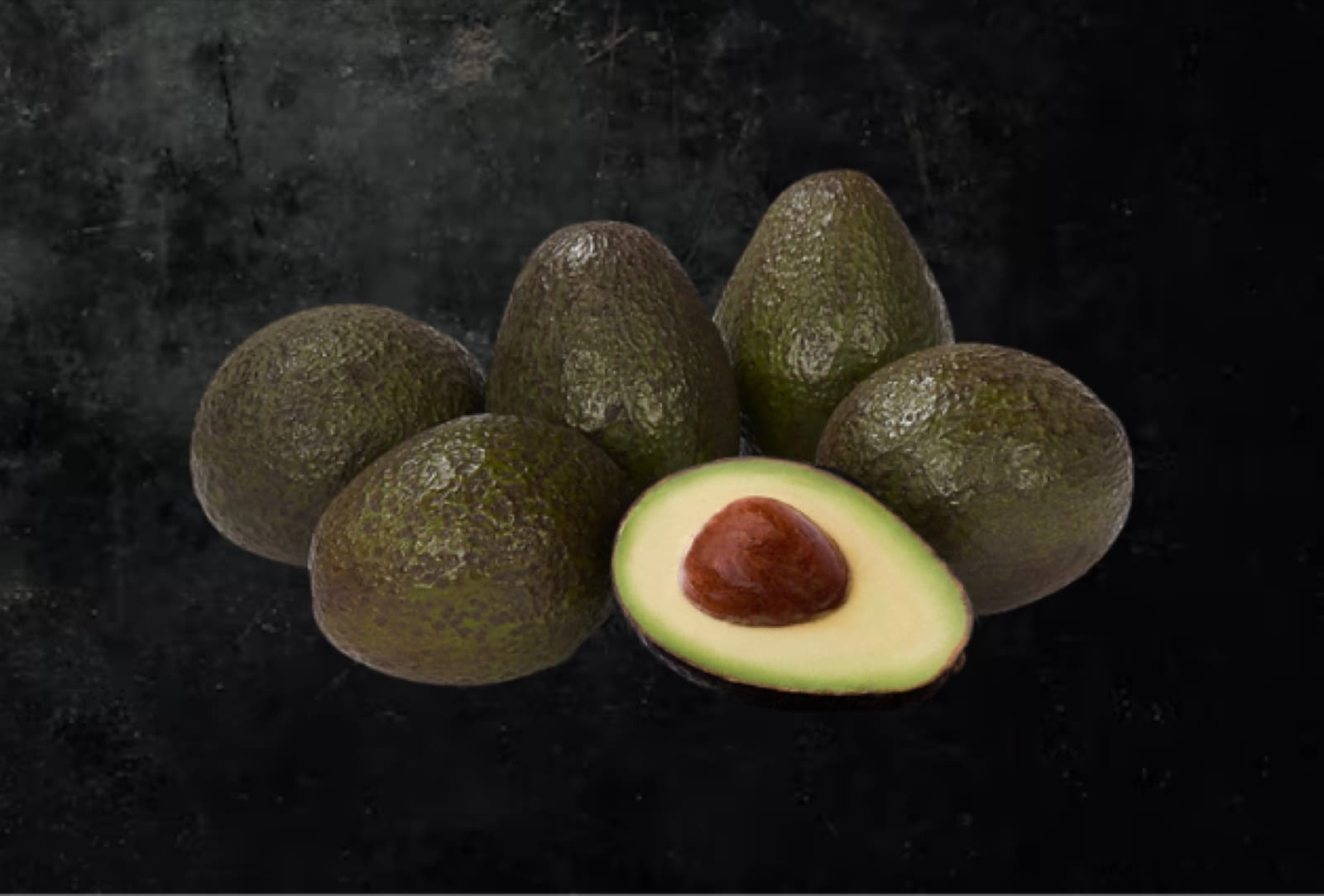 Six premium avocados with one cut open against a dark background